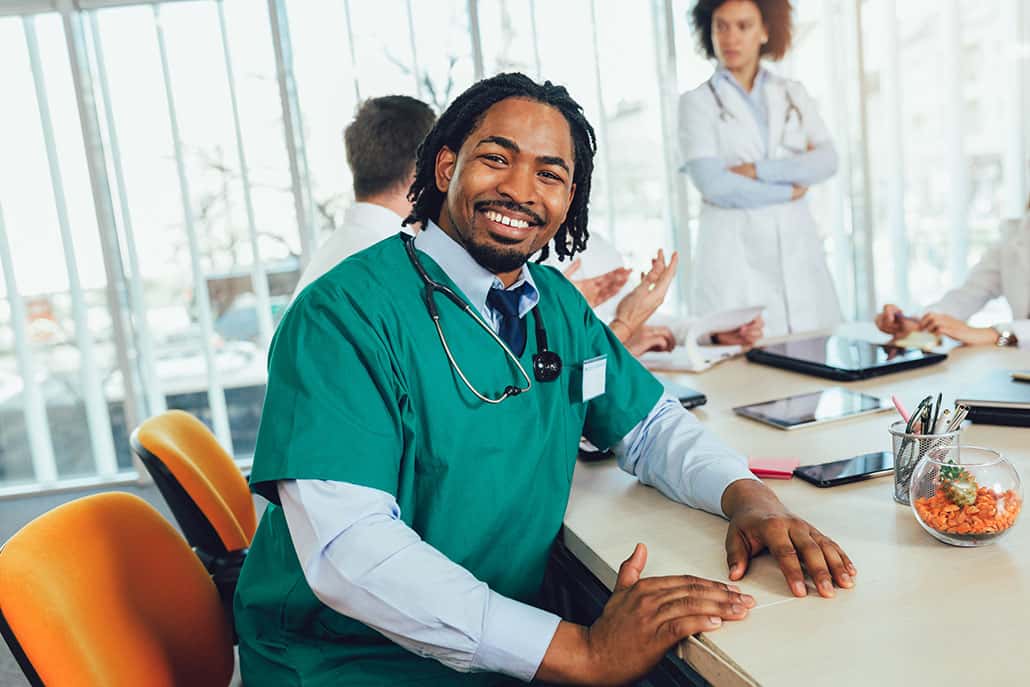 Handsome african american medical doctor with colleagues in back
